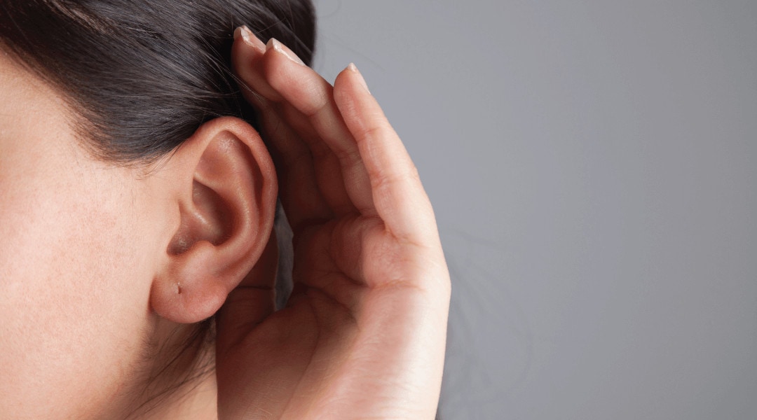 close up of a person cupping their hand around the back of their ear