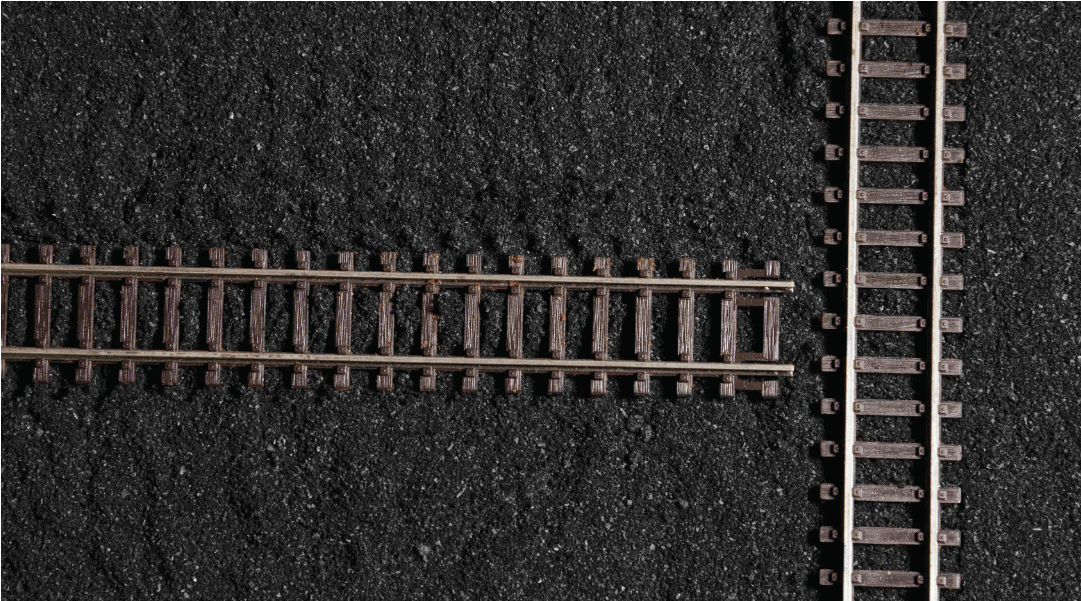 two wooden train tracks running perpendicular and ending before crossing over