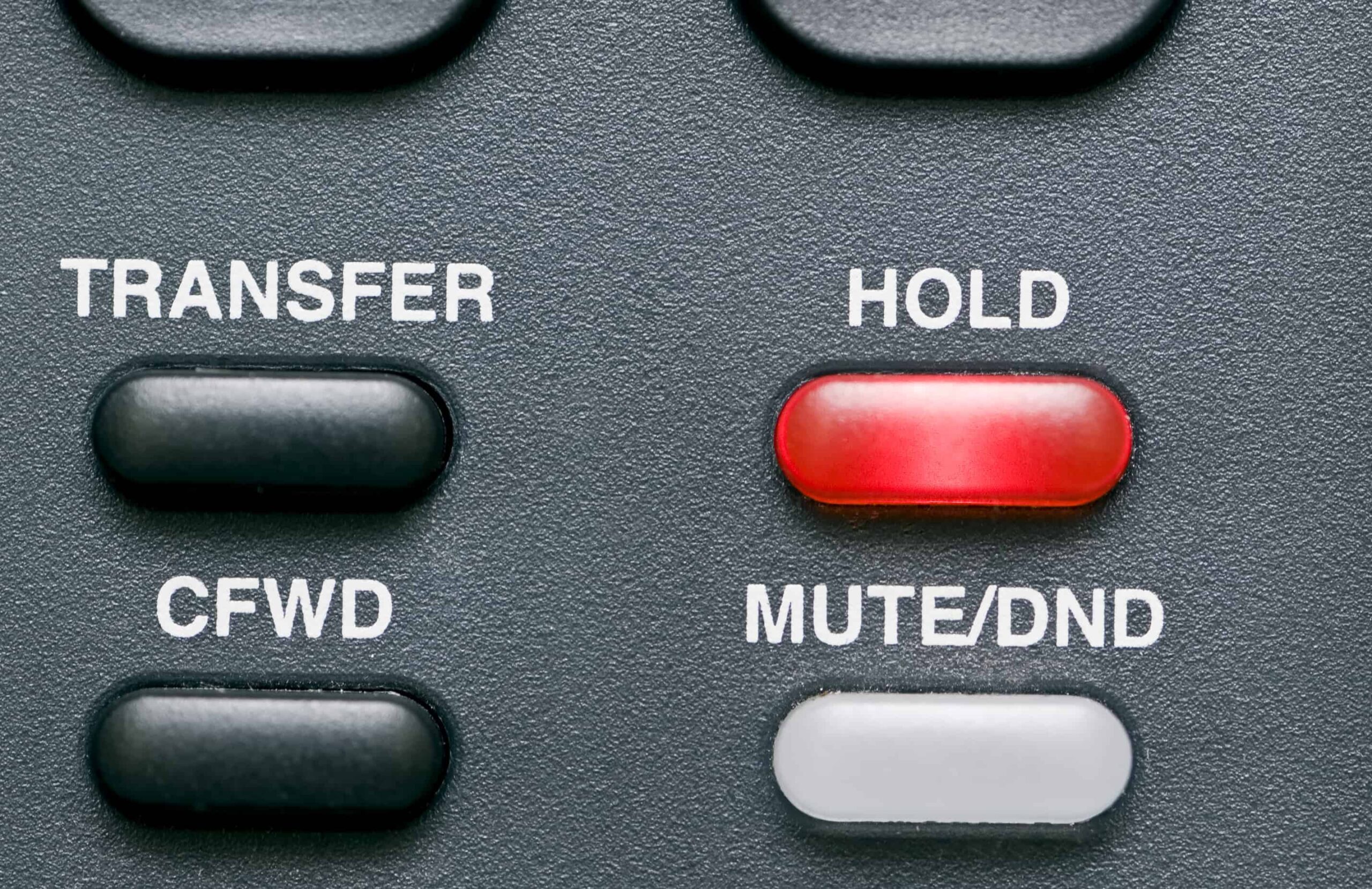 Macro shot of a telephone's feature buttons with the hold button red and activated.