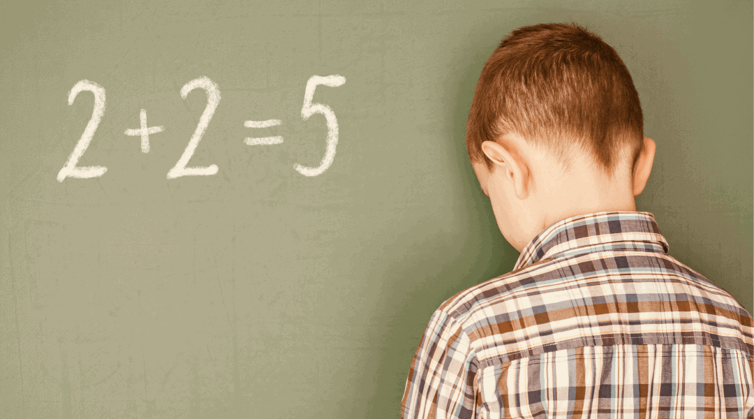 Boy at chalkboard looking sad after getting math equation wrong.
