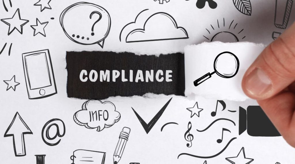 Hand pulls away piece of white paper uncovering the word "compliance"