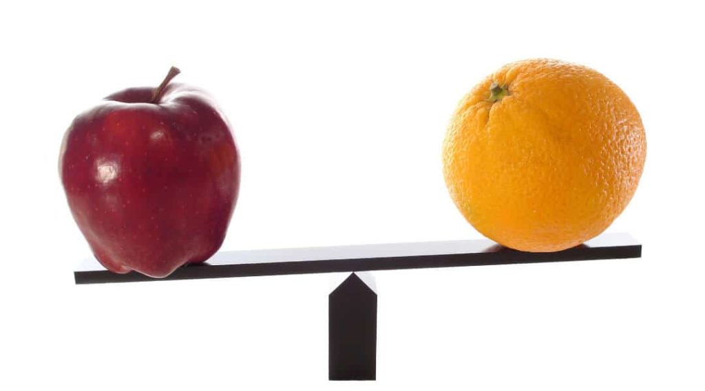 red apple and orange on either side of a seesaw