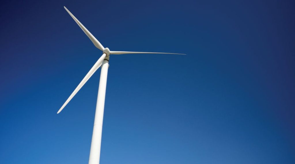 white wind turbine against a clear blue sky.