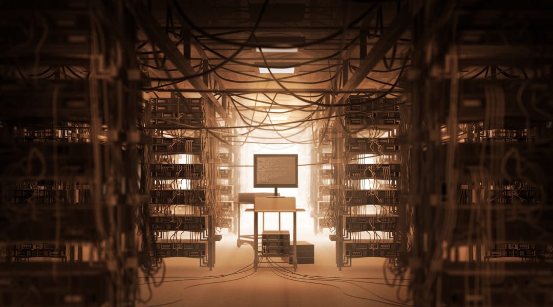 a single desktop monitor connected to and surrounded by rows of physical servers