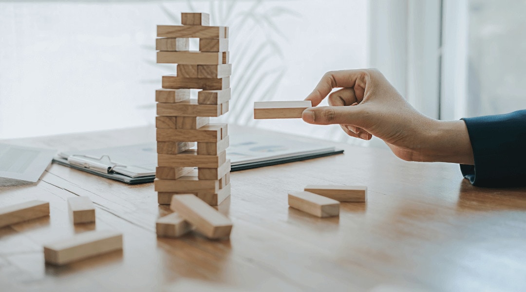 An individual pulling out a block from the wooden block stacked game, Jenga