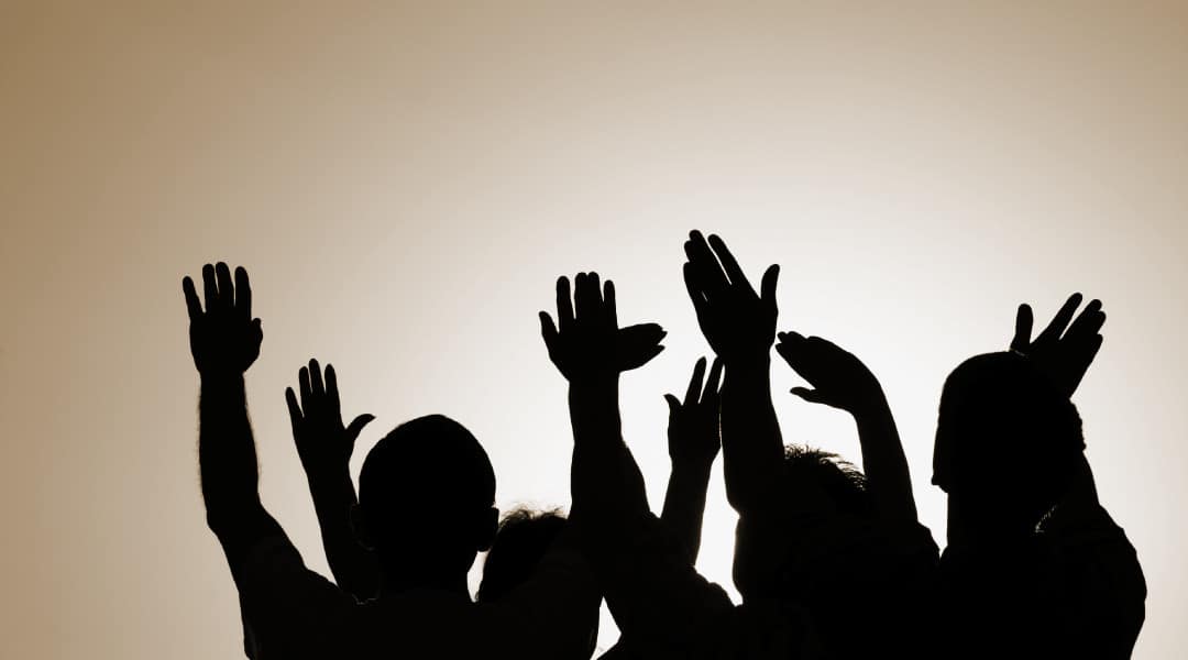 gold backdrop with a black silhouette of people waving their hands in the air.