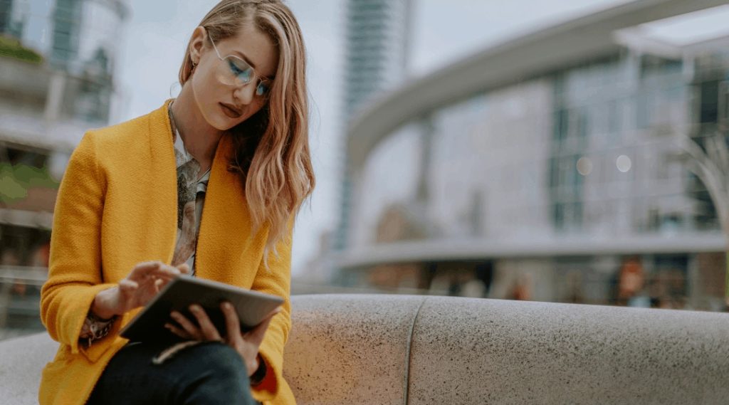 a professional individual sitting outside scrolling on her tablet