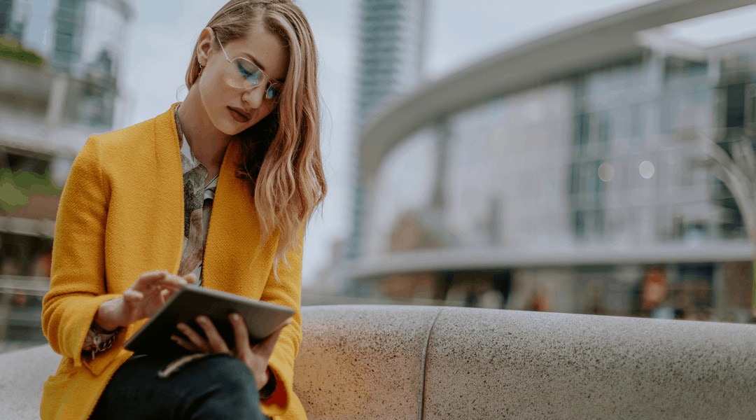 a professional individual sitting outside scrolling on her tablet