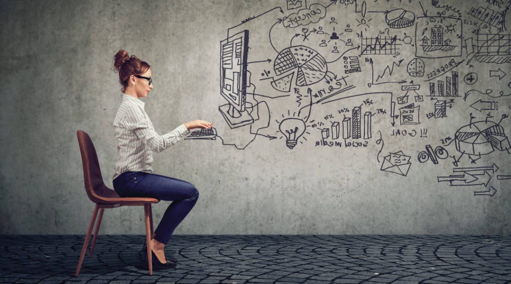 an individual sitting on a chair to make it look like she is working on the computer that is draw on the concrete wall behind her.
