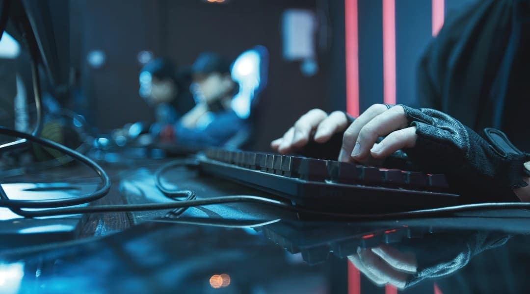 Closeup side view of person using desktop in dark room, focus on male hands on brightly lit background