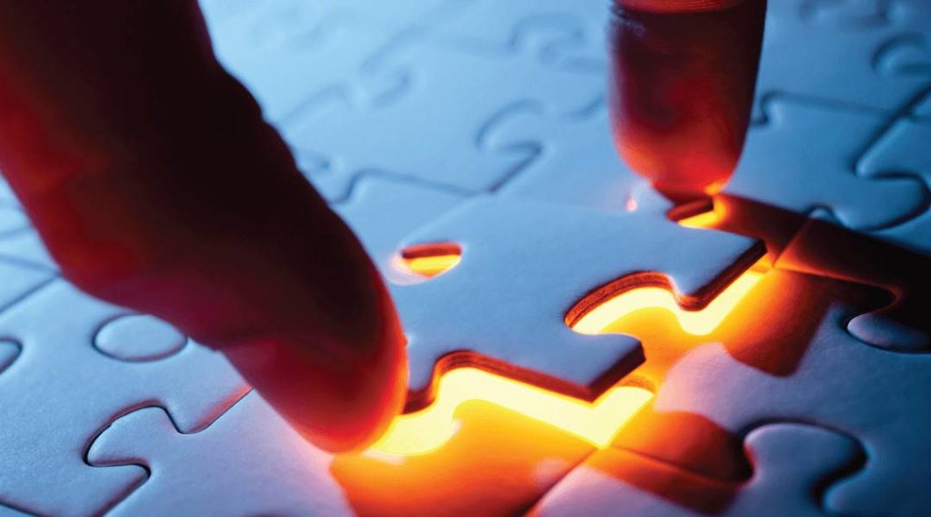 close up of a person placing the final puzzle piece into its brightly yellow glowing place.