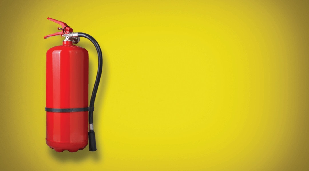 red fire extinguisher on yellow wall