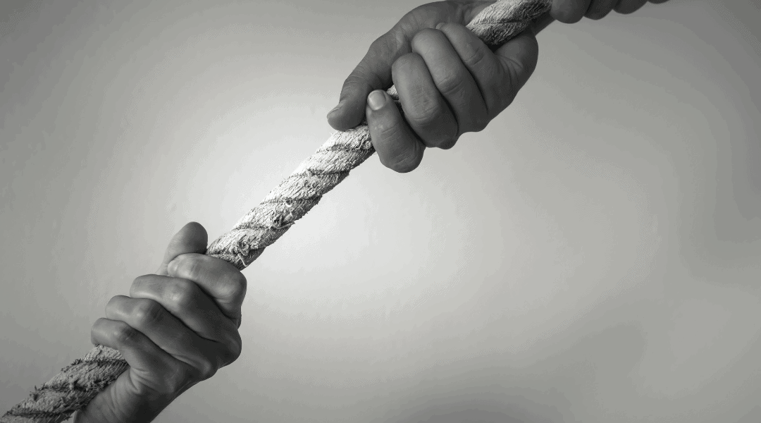 close up of individuals hands pulling on a twin rope from opposite sides.