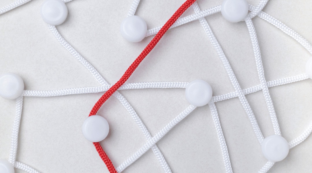 one red string amongst a few white strings connecting to and around different dots.