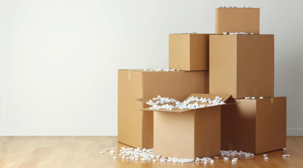 brown cardboard boxes stacked with overspilling white packing peanuts.
