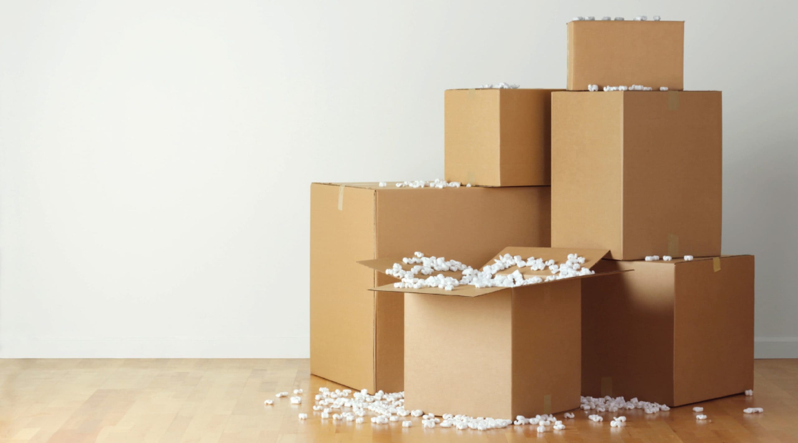 brown cardboard boxes stacked with overspilling white packing peanuts.