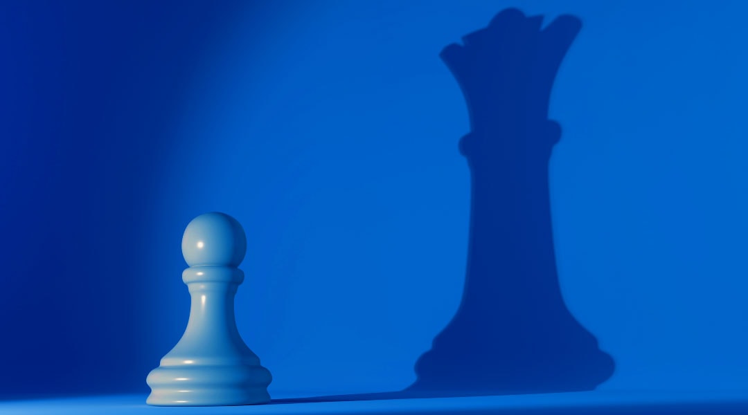 blue pawn chess piece with its shadow showing a queen chess piece