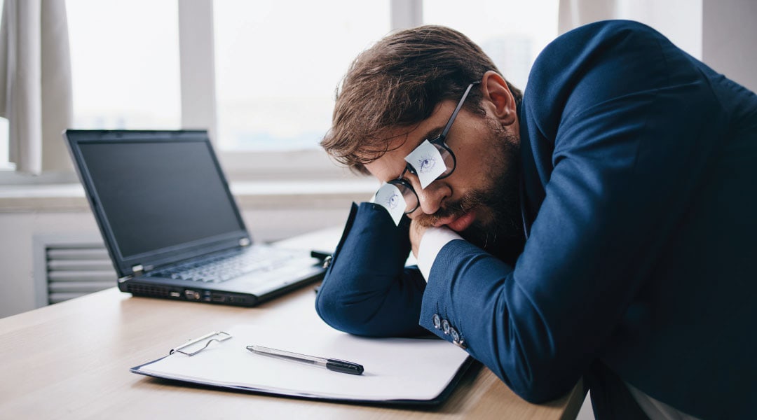 profession individual wearing glasses with drawn on open eyes resting at his desk