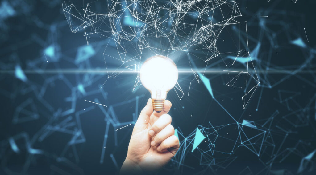 a hand holding a lit lightbulb that is surrounded by blue lines and nodes